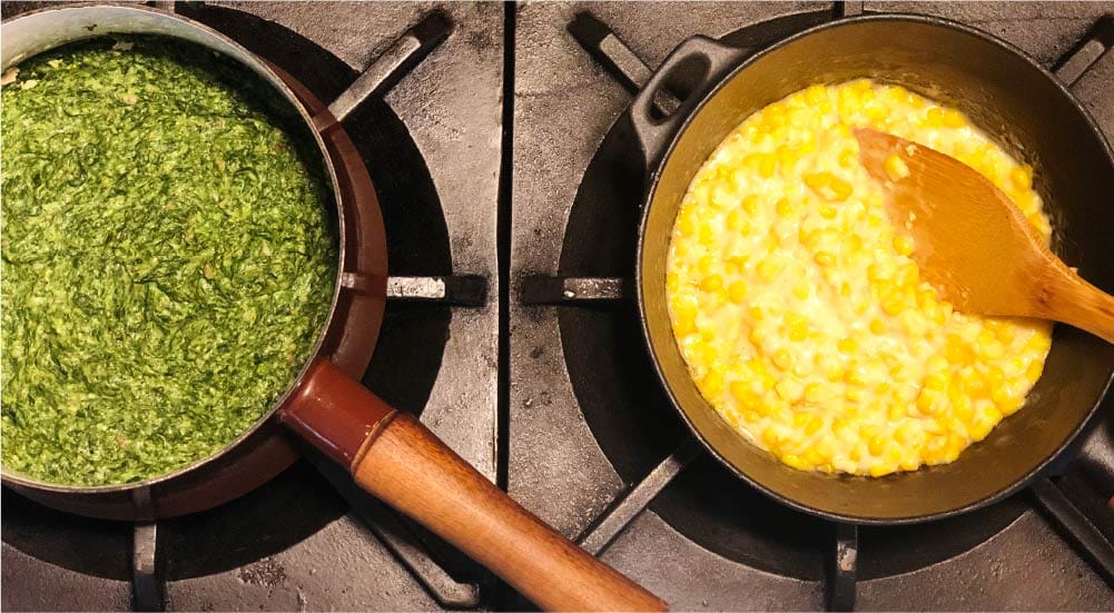 saucepans on a stove with creamed corn and creamed spinnach